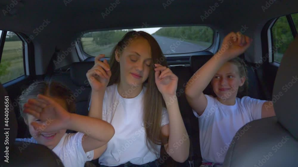 A happy family travels by car. Three sisters sit in the back of a car and have fun on the road. A happy family travels by car. Three sisters sit in the back of a car and have fun on the road.