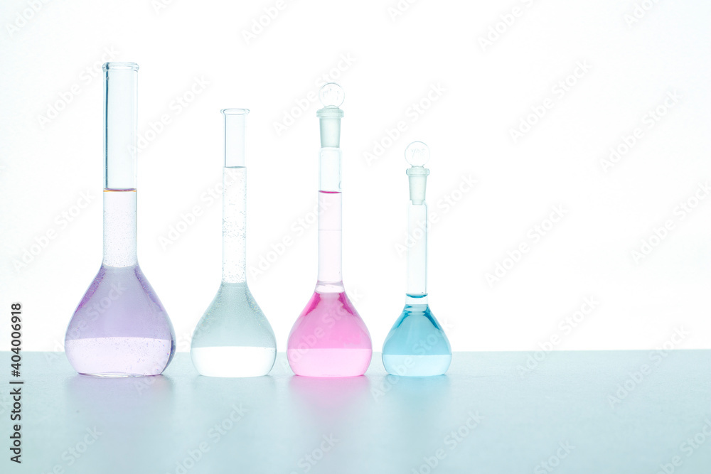 Transparent flasks with colored reagent on a white background isolated. Arranged in one row. Selective focus. Medical, science and health care concept. Transparent flasks with colored reagent on a white background isolated. Arranged in one row. Selective focus. Medical, science and health care concept.