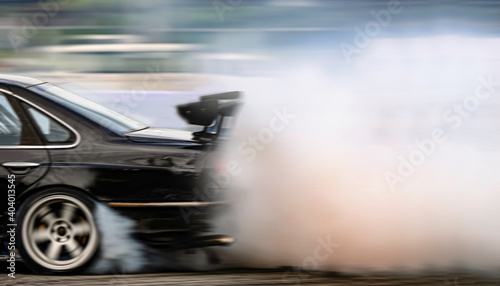 Motion blurred of image car drifting with lots of smoke from burning tires on speed track.