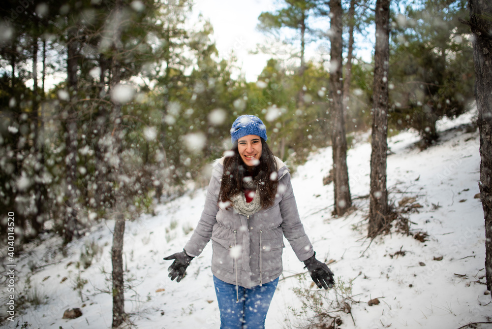 pretty brunette woman enjoying the snow on the snowy mountain with blue hat and winter coat and it is snowing pretty brunette woman enjoying the snow on the snowy mountain with blue hat and winter coat and it is snowing