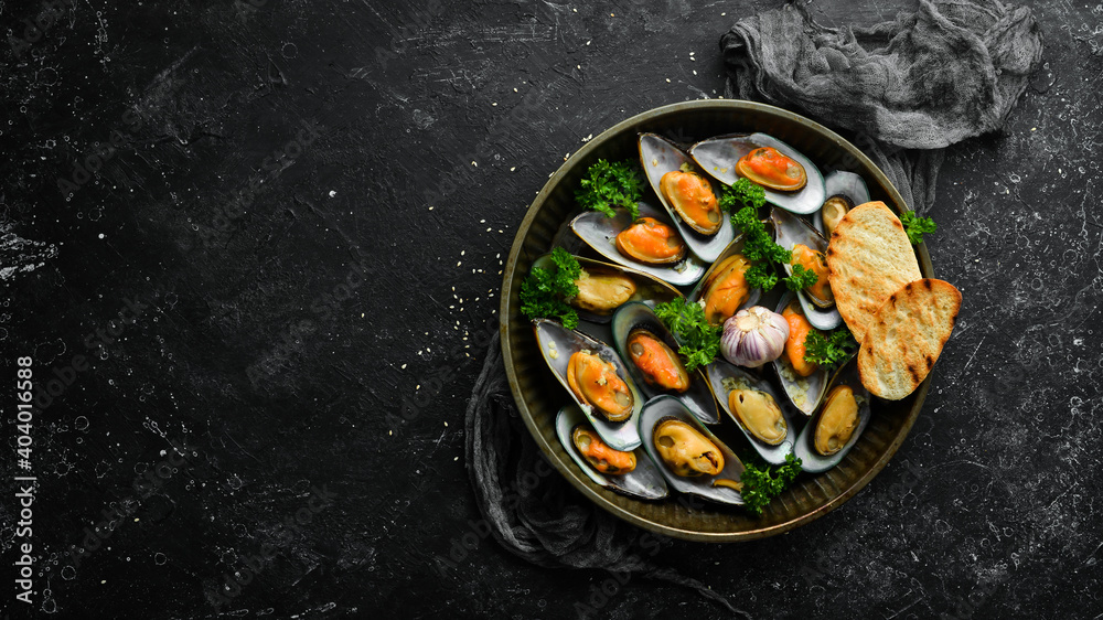 Cooked large green mussels with garlic, parsley and lemon on a metal tray. Seafood. Free space for text.