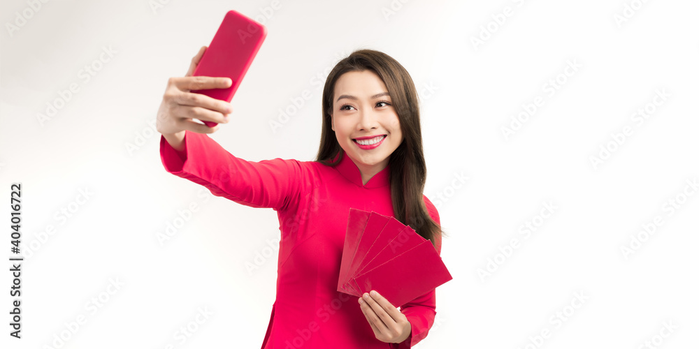 Beautiful young Asian woman in traditional costumes taking selfie at Tet celebration Beautiful young Asian woman in traditional costumes taking selfie at Tet celebration