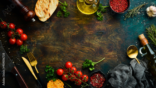 Food background: spices, vegetables and cutlery on a dark table. Free space for your text.