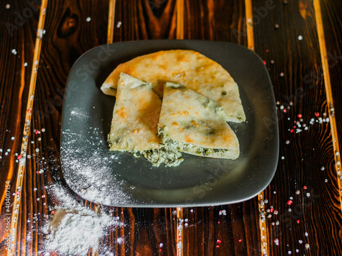 Georgian khachapuri with herbs on a wooden surface.
