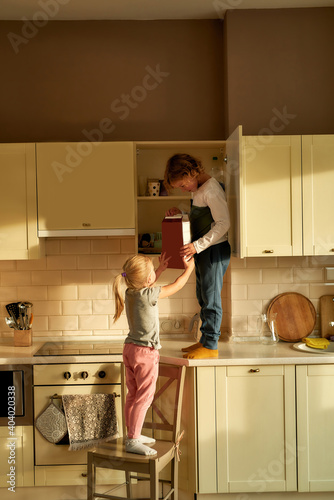 Two naughty kids, brother and sister found cookies box in the kitchen cabinet © Svitlana