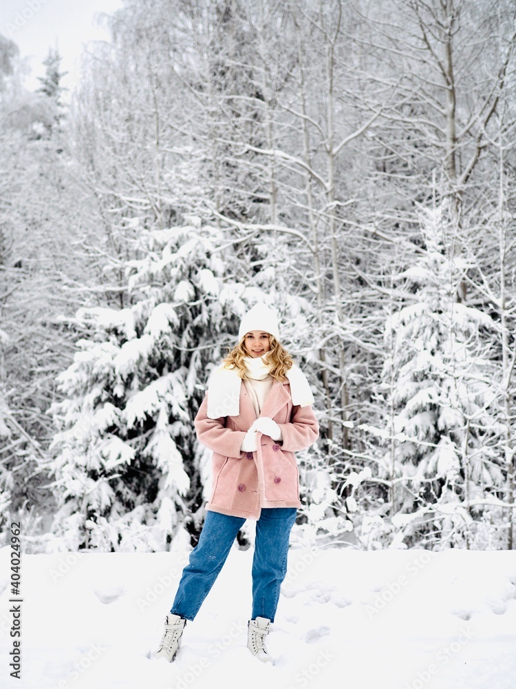Portrait of a young smiling woman wearing a white knitted hat, scarf, mittens and sweater in winter time outdoors. Fashion. Enjoying nature Portrait of a young smiling woman wearing a white knitted hat, scarf, mittens and sweater in winter time outdoors. Fashion. Enjoying nature