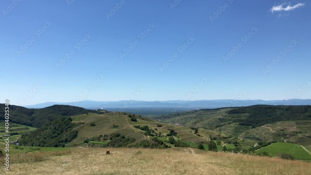 Beautiful view of a vineyard terraces and a village in the valley at Kaiserstuhl, Germany under a clear blue sky. The Rhine valley and the French Vosges mountains are in background. Beautiful view of a vineyard terraces and a village in the valley at Kaiserstuhl, Germany under a clear blue sky. The Rhine valley and the French Vosges mountains are in background.