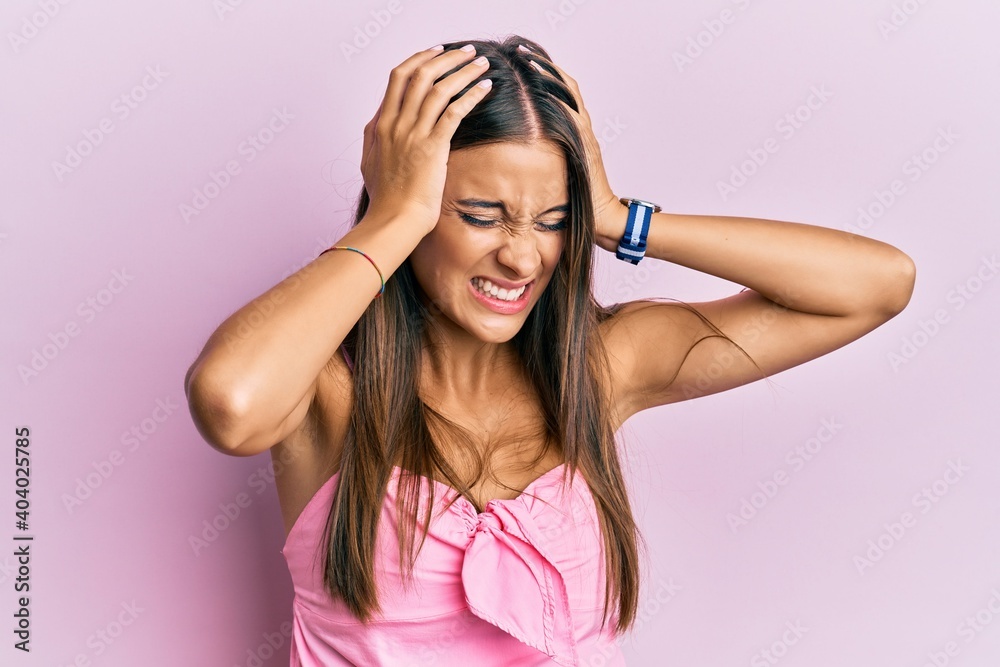 Young hispanic woman wearing casual style with sleeveless shirt suffering from headache desperate and stressed because pain and migraine. hands on head.