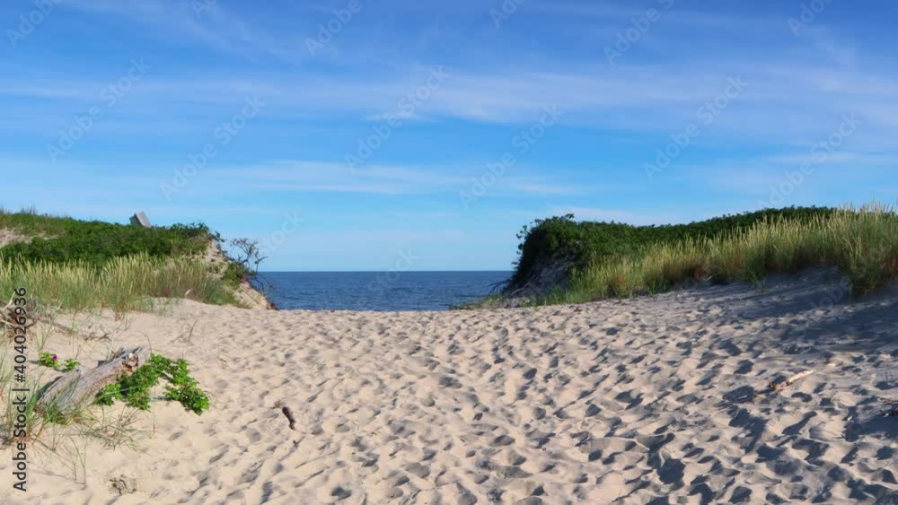 Way to sandy beach at Baltic Sea. A summer morning with a sunny clear blue sky. Sandy dunes with coastal grass. A sandy pathway to the Baltic Sea. Way to sandy beach at Baltic Sea. A summer morning with a sunny clear blue sky. Sandy dunes with coastal grass. A sandy pathway to the Baltic Sea.