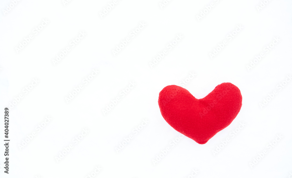 Valentines day greeting card and lot of empty space for your greeting text. Small red soft toy heart lies on white snow.