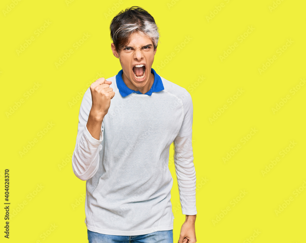 Young hispanic man wearing casual clothes angry and mad raising fist frustrated and furious while shouting with anger. rage and aggressive concept. Young hispanic man wearing casual clothes angry and mad raising fist frustrated and furious while shouting with anger. rage and aggressive concept.