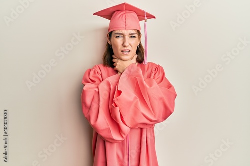 Young caucasian woman wearing graduation cap and ceremony robe shouting and suffocate because painful strangle. health problem. asphyxiate and suicide concept.
