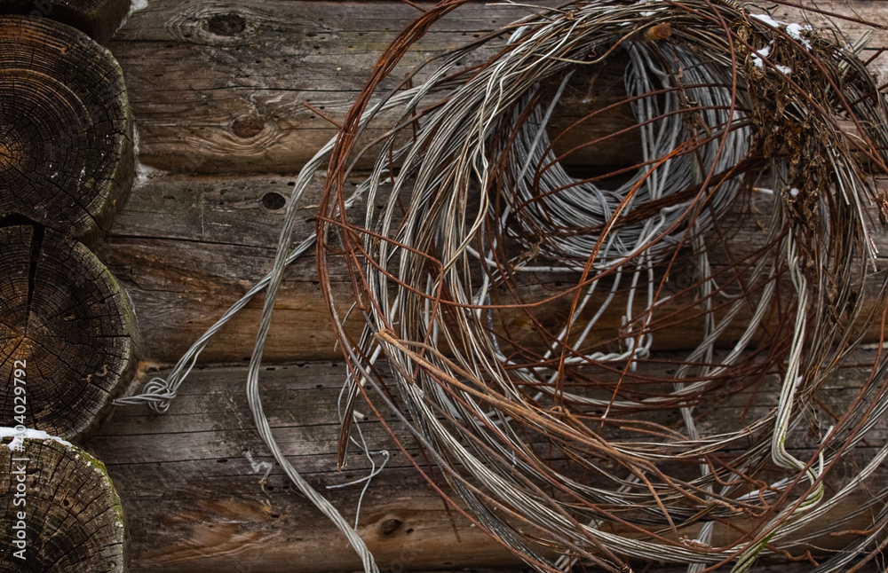 Many kinds of wire hangs on a nail on the wall of a wooden structure in the village