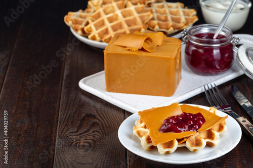 Homemade waffles with norvegian brown cheese and lingon jam, on wooden background, horizontal, copy space photo