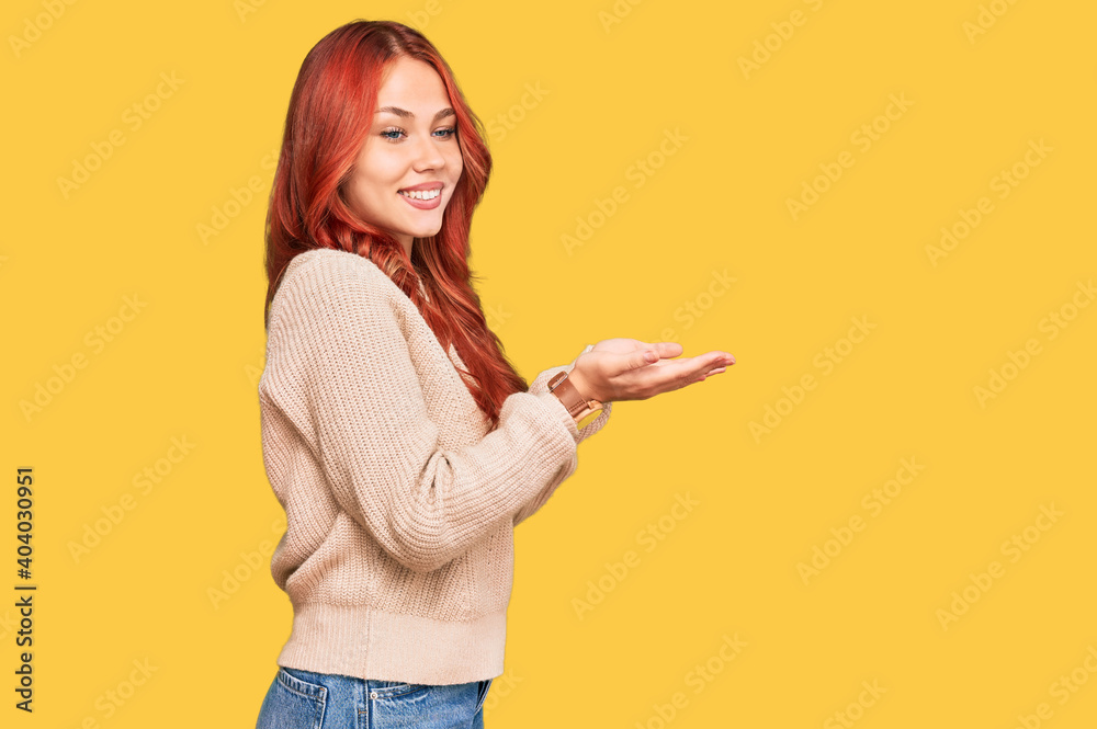 Young redhead woman wearing casual winter sweater pointing aside with hands open palms showing copy space, presenting advertisement smiling excited happy Young redhead woman wearing casual winter sweater pointing aside with hands open palms showing copy space, presenting advertisement smiling excited happy