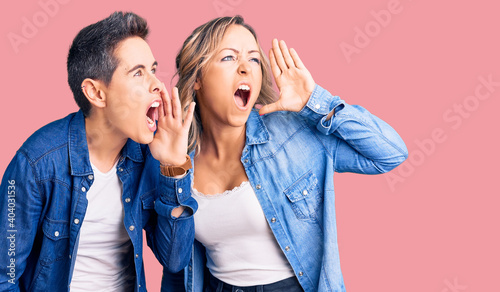 Couple of women wearing casual clothes shouting and screaming loud to side with hand on mouth. communication concept.