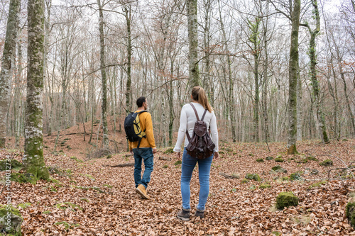 Couple walking with backpacks in amazing autumnal forest.Hiking , travel wanderlust concept.Love friendship lifestyle.