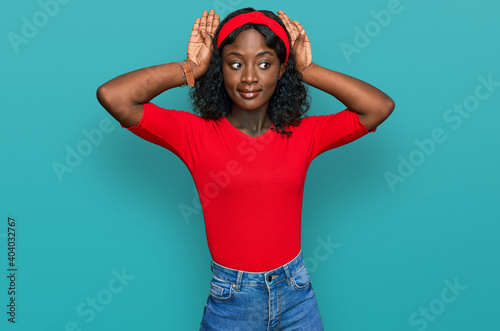 Beautiful african young woman wearing casual clothes doing bunny ears gesture with hands palms looking cynical and skeptical. easter rabbit concept. photo