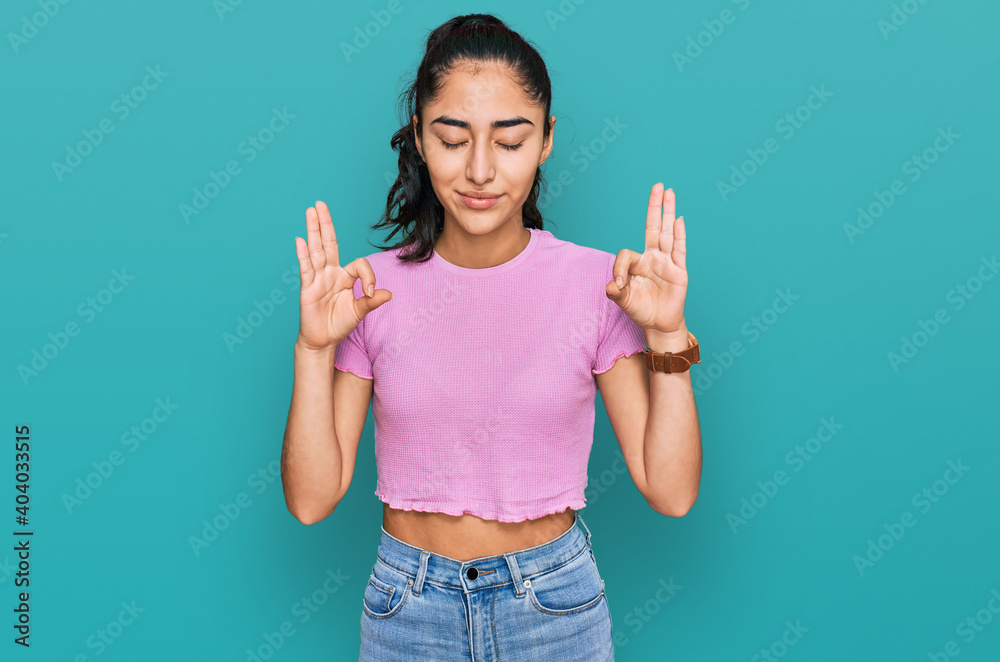 Hispanic teenager girl with dental braces wearing casual clothes relaxed and smiling with eyes closed doing meditation gesture with fingers. yoga concept. Hispanic teenager girl with dental braces wearing casual clothes relaxed and smiling with eyes closed doing meditation gesture with fingers. yoga concept.