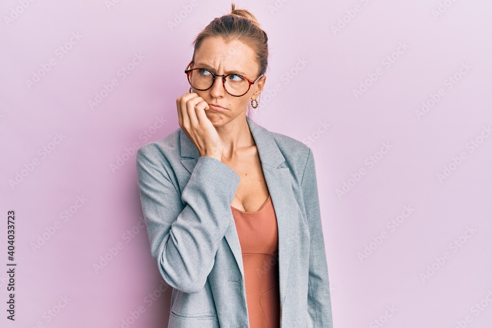 Beautiful caucasian woman wearing business jacket and glasses looking stressed and nervous with hands on mouth biting nails. anxiety problem.
