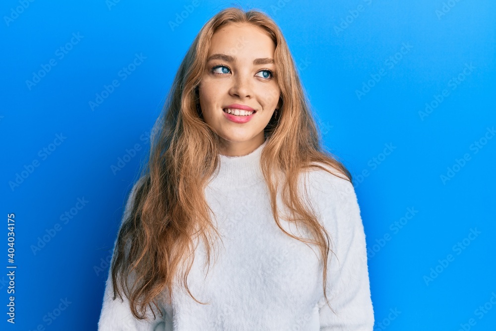 Fototapeta premium Beautiful blonde caucasian woman wearing casual winter sweater looking to side, relax profile pose with natural face and confident smile.
