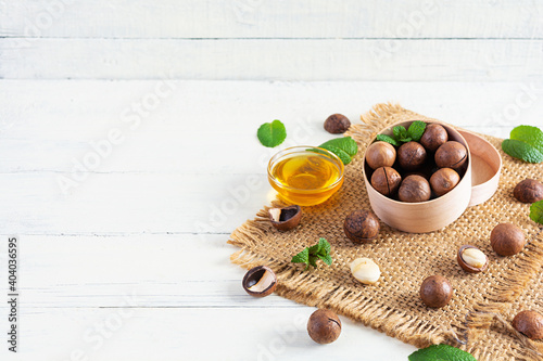 Macadamia nuts in shell with mint leaves and honey on wooden background