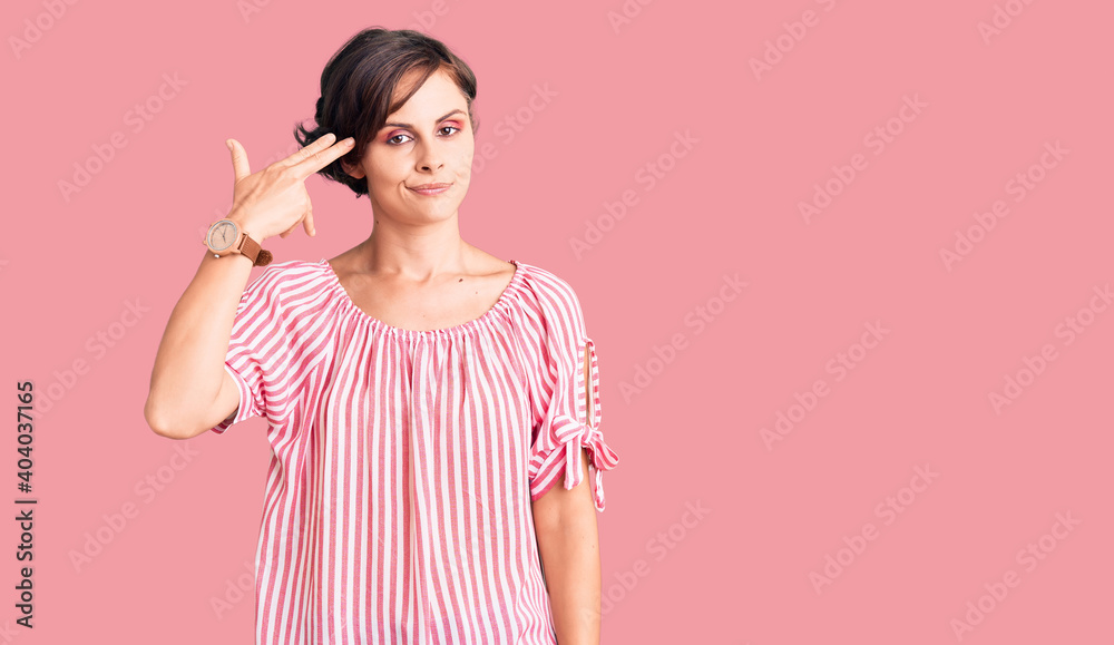 Beautiful young woman with short hair wearing casual summer clothes shooting and killing oneself pointing hand and fingers to head like gun, suicide gesture. Beautiful young woman with short hair wearing casual summer clothes shooting and killing oneself pointing hand and fingers to head like gun, suicide gesture.