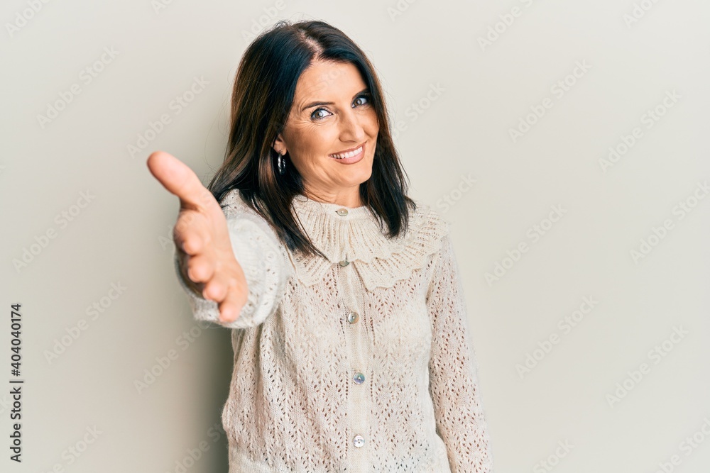 Middle age brunette woman wearing casual clothes smiling friendly offering handshake as greeting and welcoming. successful business. Middle age brunette woman wearing casual clothes smiling friendly offering handshake as greeting and welcoming. successful business.