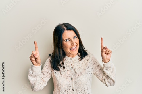 Middle age brunette woman pointing up with fingers smiling and laughing hard out loud because funny crazy joke.