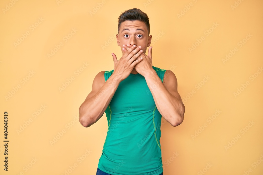 Young hispanic boy wearing sporty style with sleeveless shirt shocked covering mouth with hands for mistake. secret concept. Young hispanic boy wearing sporty style with sleeveless shirt shocked covering mouth with hands for mistake. secret concept.
