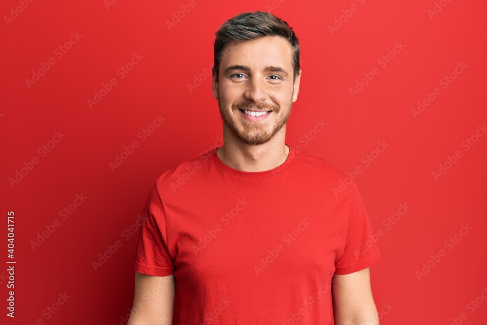 Handsome caucasian man wearing casual red tshirt with a happy and cool smile on face. lucky person. Handsome caucasian man wearing casual red tshirt with a happy and cool smile on face. lucky person.