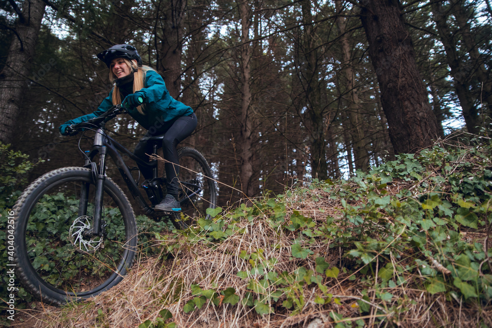 Cyclist girl with mountain bike descending down mtb trail in forest