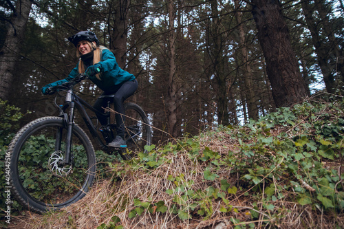 Cyclist girl with mountain bike descending down mtb trail in forest