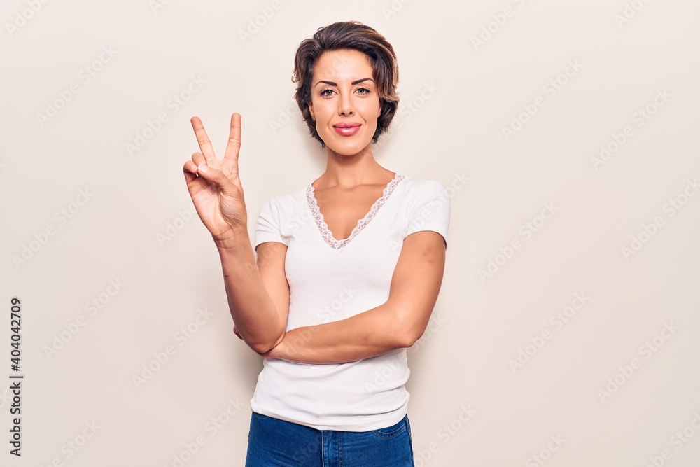 Young beautiful woman wearing casual clothes showing and pointing up with fingers number two while smiling confident and happy. Young beautiful woman wearing casual clothes showing and pointing up with fingers number two while smiling confident and happy.