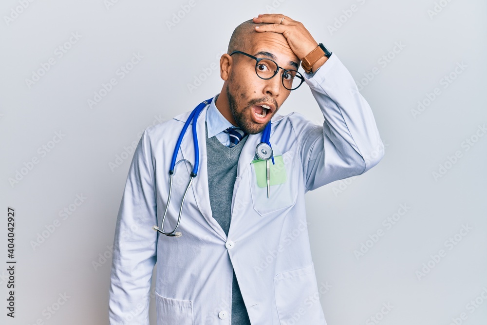 Hispanic adult man wearing doctor uniform and stethoscope surprised with hand on head for mistake, remember error. forgot, bad memory concept. Hispanic adult man wearing doctor uniform and stethoscope surprised with hand on head for mistake, remember error. forgot, bad memory concept.