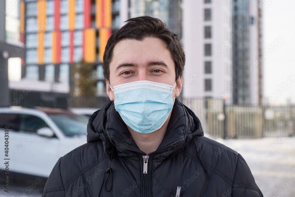 a young man in a jacket wearing a protective medical mask on his face. protective mask on the face of the virus and contamination a young man in a jacket wearing a protective medical mask on his face. protective mask on the face of the virus and contamination