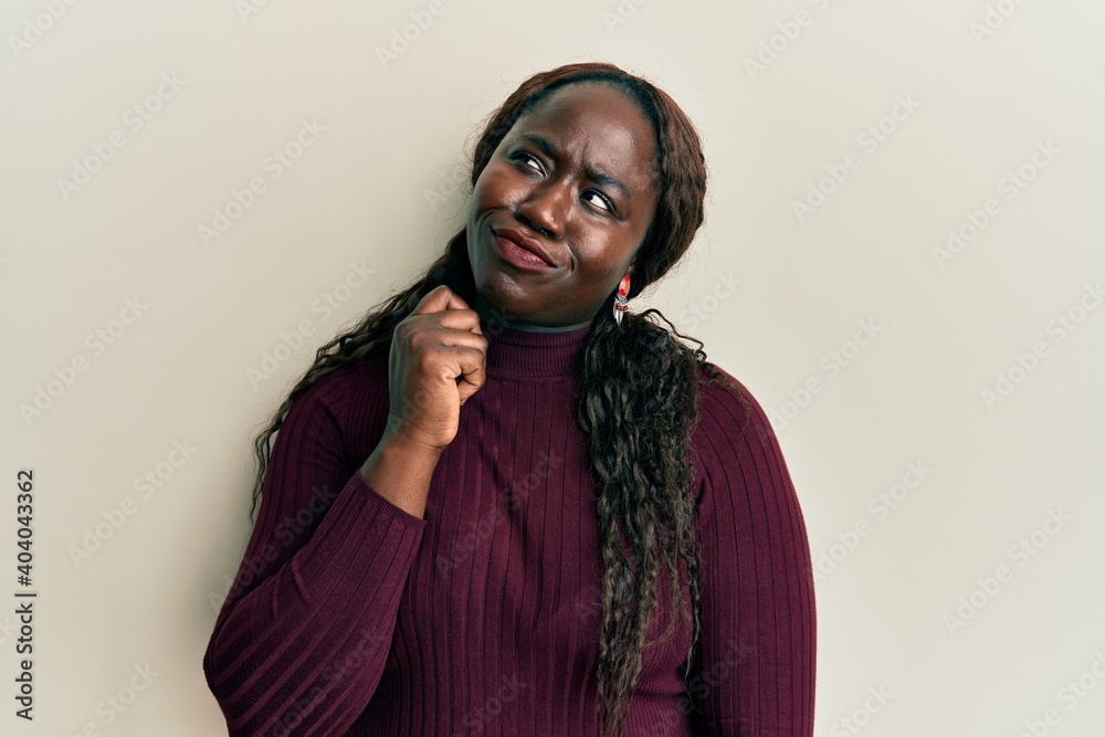 African young woman wearing casual clothes thinking concentrated about doubt with finger on chin and looking up wondering African young woman wearing casual clothes thinking concentrated about doubt with finger on chin and looking up wondering