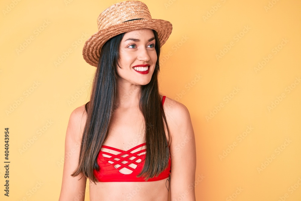 Young beautiful caucasian woman wearing bikini and hat looking to side, relax profile pose with natural face and confident smile. Young beautiful caucasian woman wearing bikini and hat looking to side, relax profile pose with natural face and confident smile.
