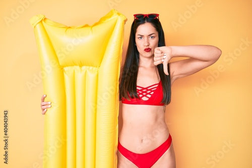 Young beautiful caucasian woman wearing bikini holding floater with angry face, negative sign showing dislike with thumbs down, rejection concept © Krakenimages.com