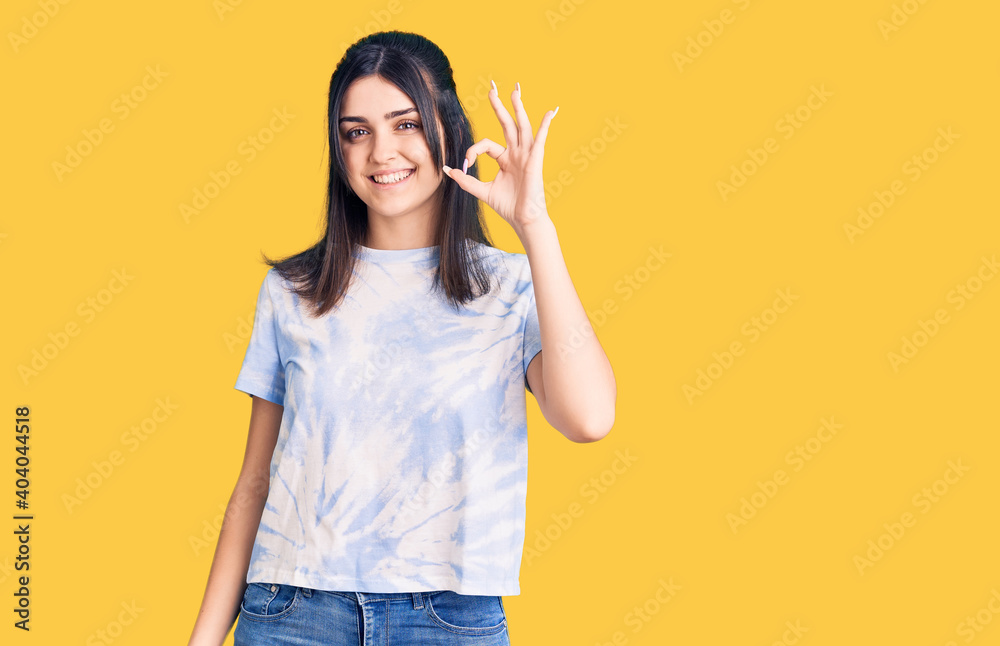 Young beautiful girl wearing casual t shirt smiling positive doing ok sign with hand and fingers. successful expression. Young beautiful girl wearing casual t shirt smiling positive doing ok sign with hand and fingers. successful expression.