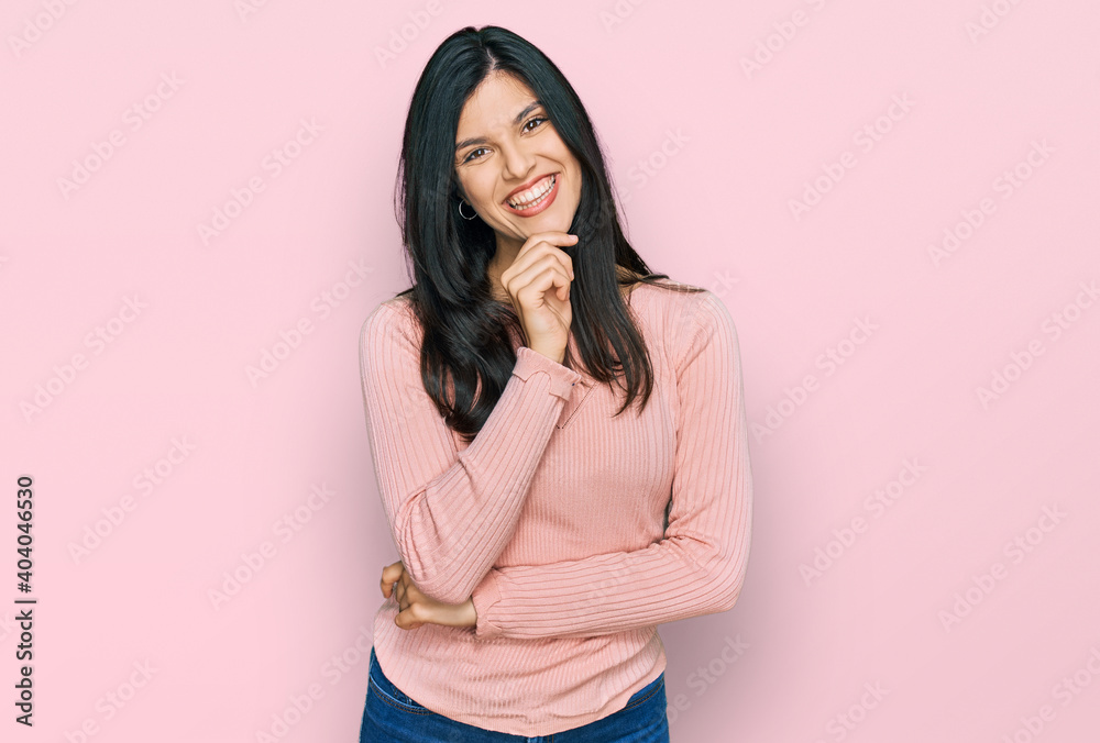 Young hispanic woman wearing casual clothes looking confident at the camera with smile with crossed arms and hand raised on chin. thinking positive. Young hispanic woman wearing casual clothes looking confident at the camera with smile with crossed arms and hand raised on chin. thinking positive.