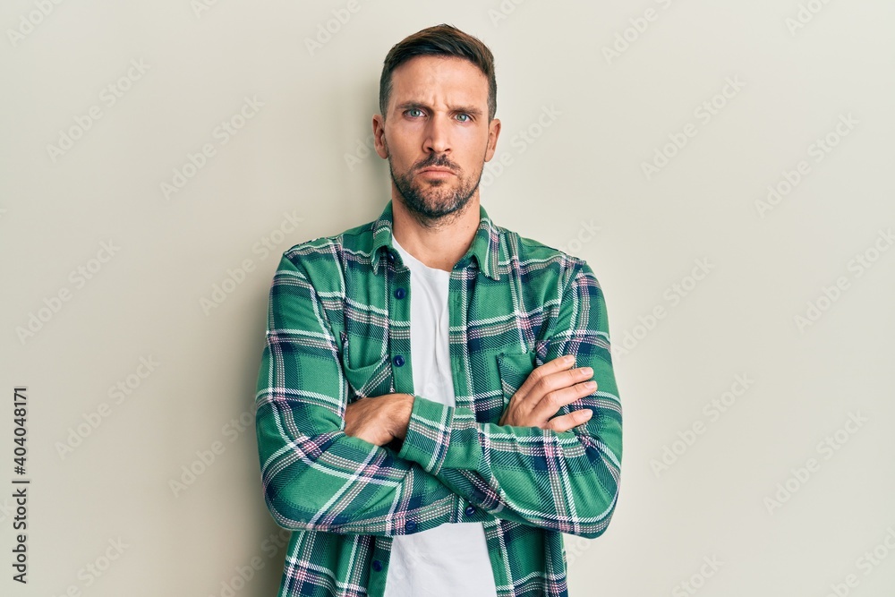 Handsome man with beard wearing casual clothes skeptic and nervous, disapproving expression on face with crossed arms. negative person. Handsome man with beard wearing casual clothes skeptic and nervous, disapproving expression on face with crossed arms. negative person.