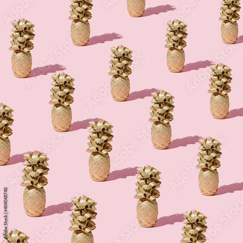 Creative concept of Christmas tree pattern in shape of pineapple, made of gold ribbon on pastel pink background.