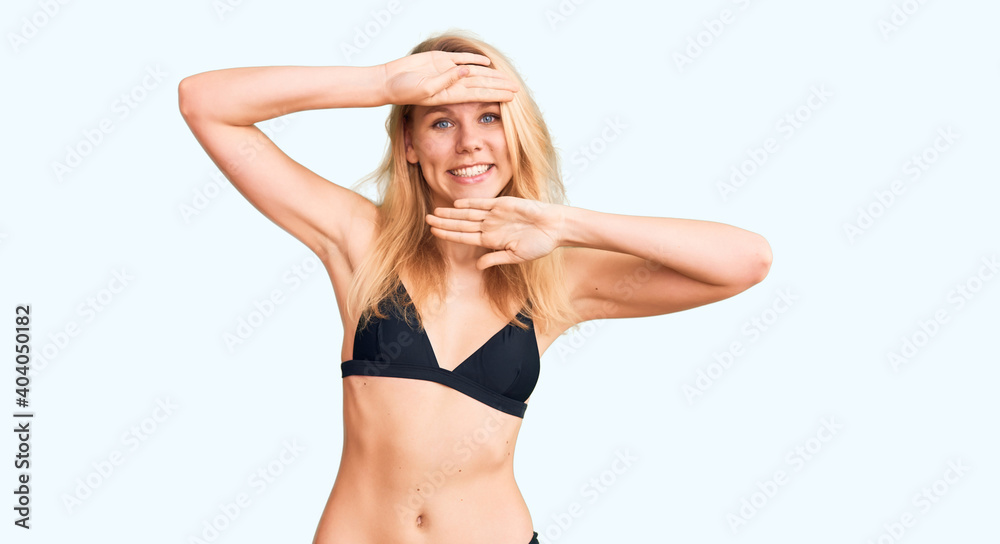 Young beautiful blonde woman wearing bikini smiling cheerful playing peek a boo with hands showing face. surprised and exited Young beautiful blonde woman wearing bikini smiling cheerful playing peek a boo with hands showing face. surprised and exited