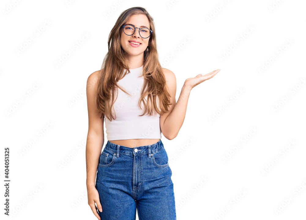 Beautiful caucasian young woman wearing casual clothes and glasses smiling cheerful presenting and pointing with palm of hand looking at the camera. Beautiful caucasian young woman wearing casual clothes and glasses smiling cheerful presenting and pointing with palm of hand looking at the camera.