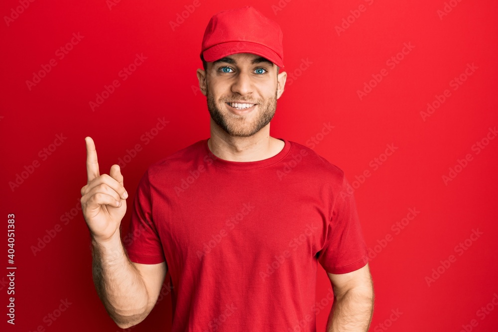 Young caucasian man wearing delivery uniform and cap smiling happy pointing with hand and finger to the side Young caucasian man wearing delivery uniform and cap smiling happy pointing with hand and finger to the side