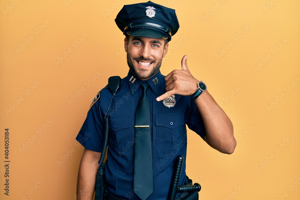 Handsome hispanic man wearing police uniform smiling doing phone gesture with hand and fingers like talking on the telephone. communicating concepts. Handsome hispanic man wearing police uniform smiling doing phone gesture with hand and fingers like talking on the telephone. communicating concepts.