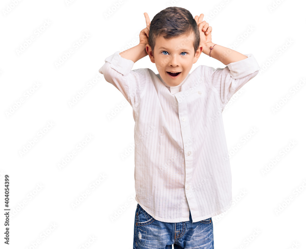 Cute blond kid wearing elegant shirt posing funny and crazy with fingers on head as bunny ears, smiling cheerful Cute blond kid wearing elegant shirt posing funny and crazy with fingers on head as bunny ears, smiling cheerful