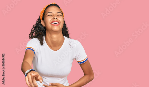 Young african american girl wearing casual clothes laughing at you, pointing finger to the camera with hand over body, shame expression