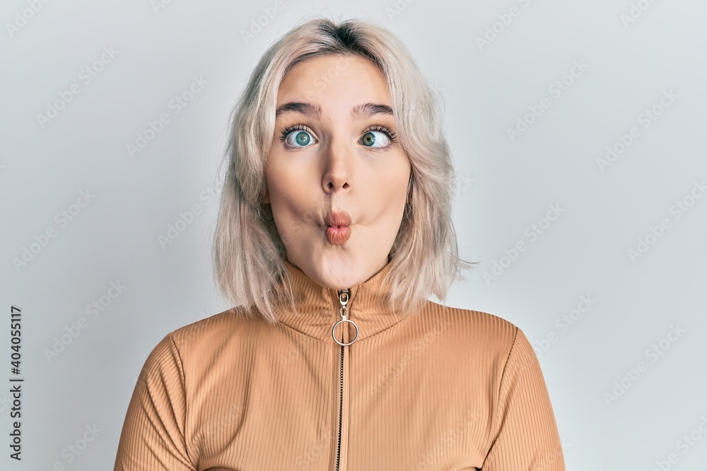 Young blonde girl wearing casual clothes making fish face with lips, crazy and comical gesture. funny expression.